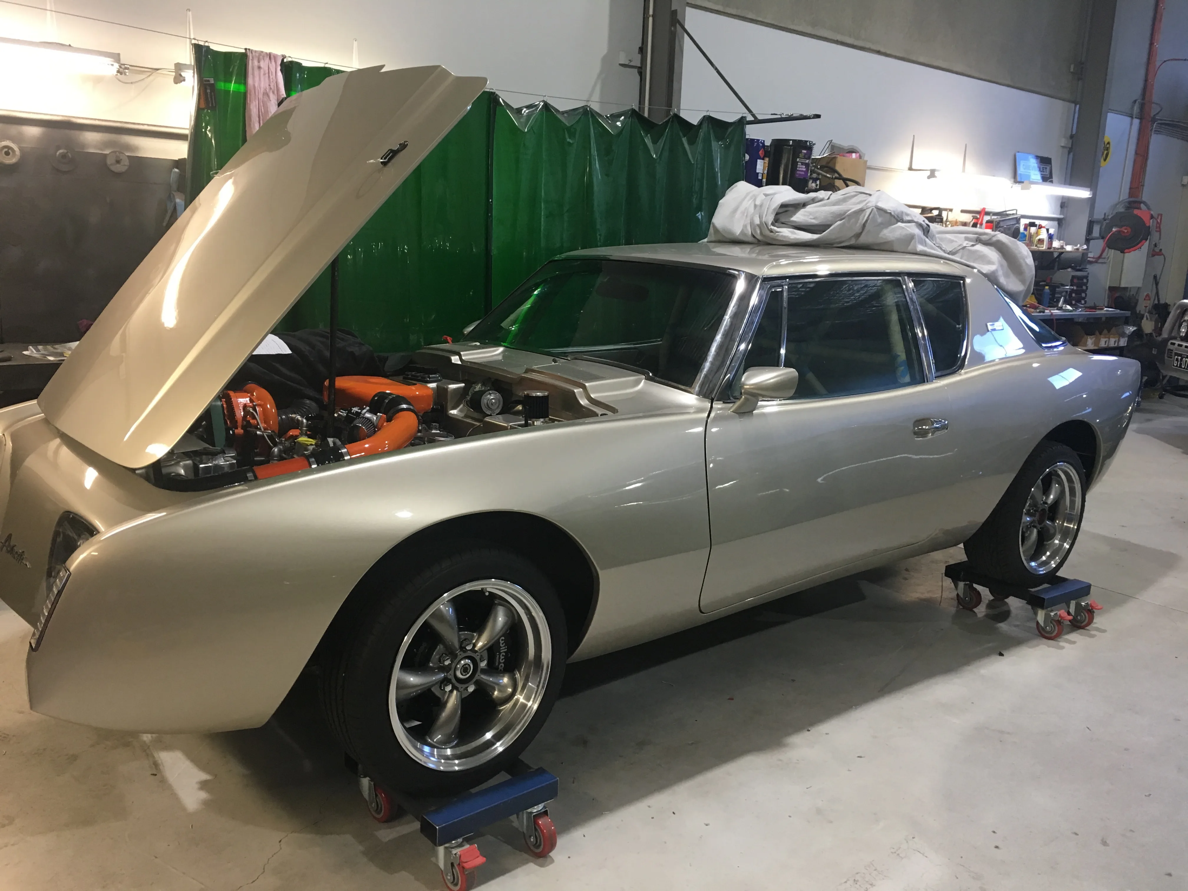 Classic car in the workshop with bonnet up showing detailed engine bay work