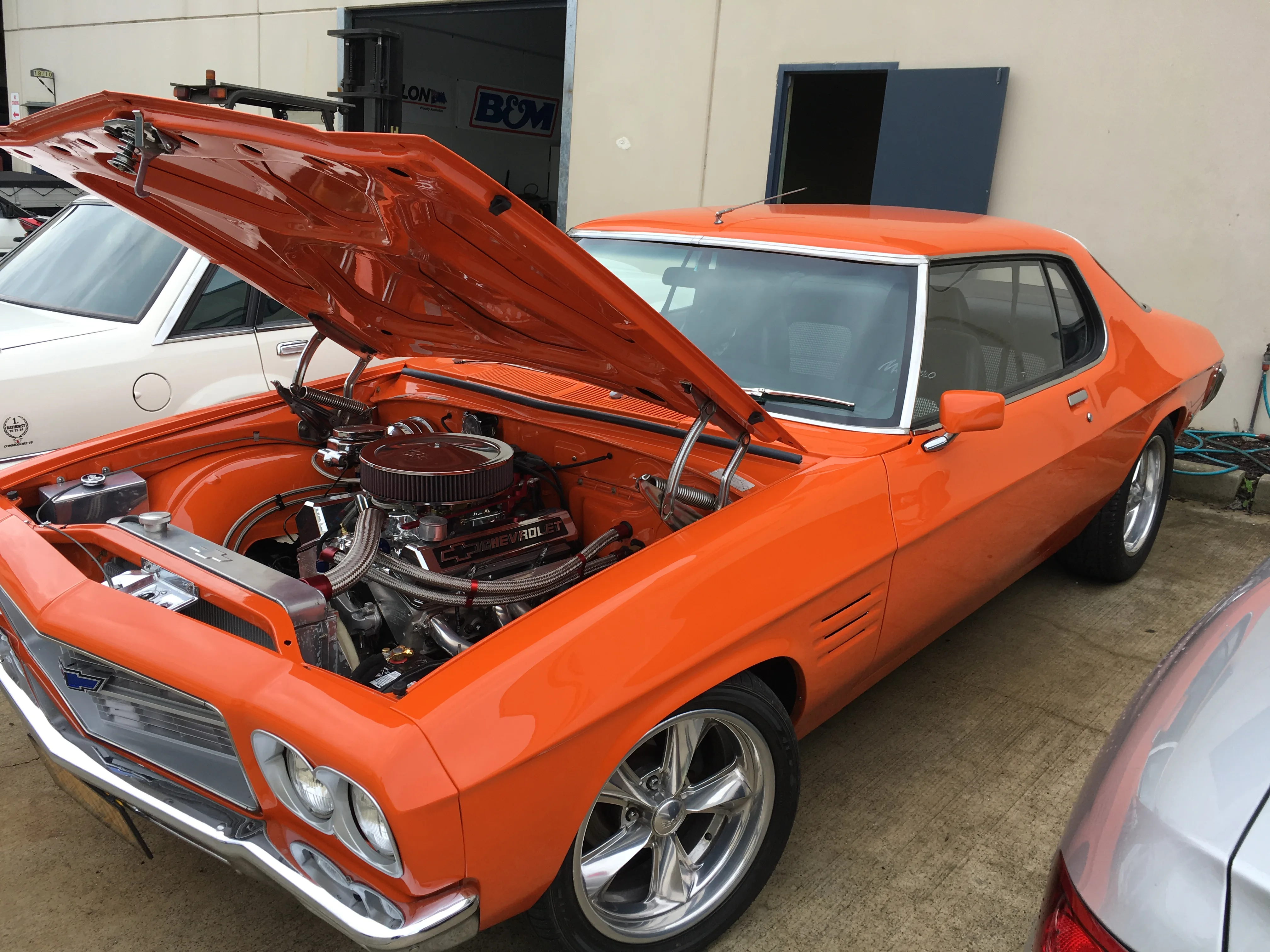 Orange classic car with bonnet open at the Totally Wired workshop